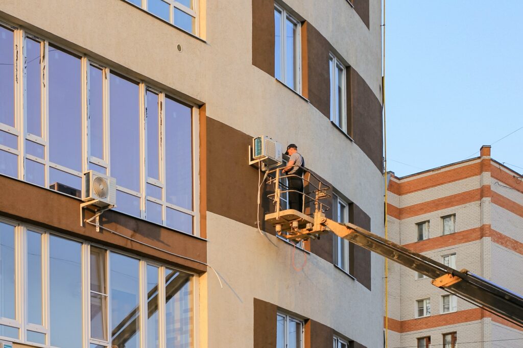 Industrial technician, engineer installing air conditioner on the facade of the house. N