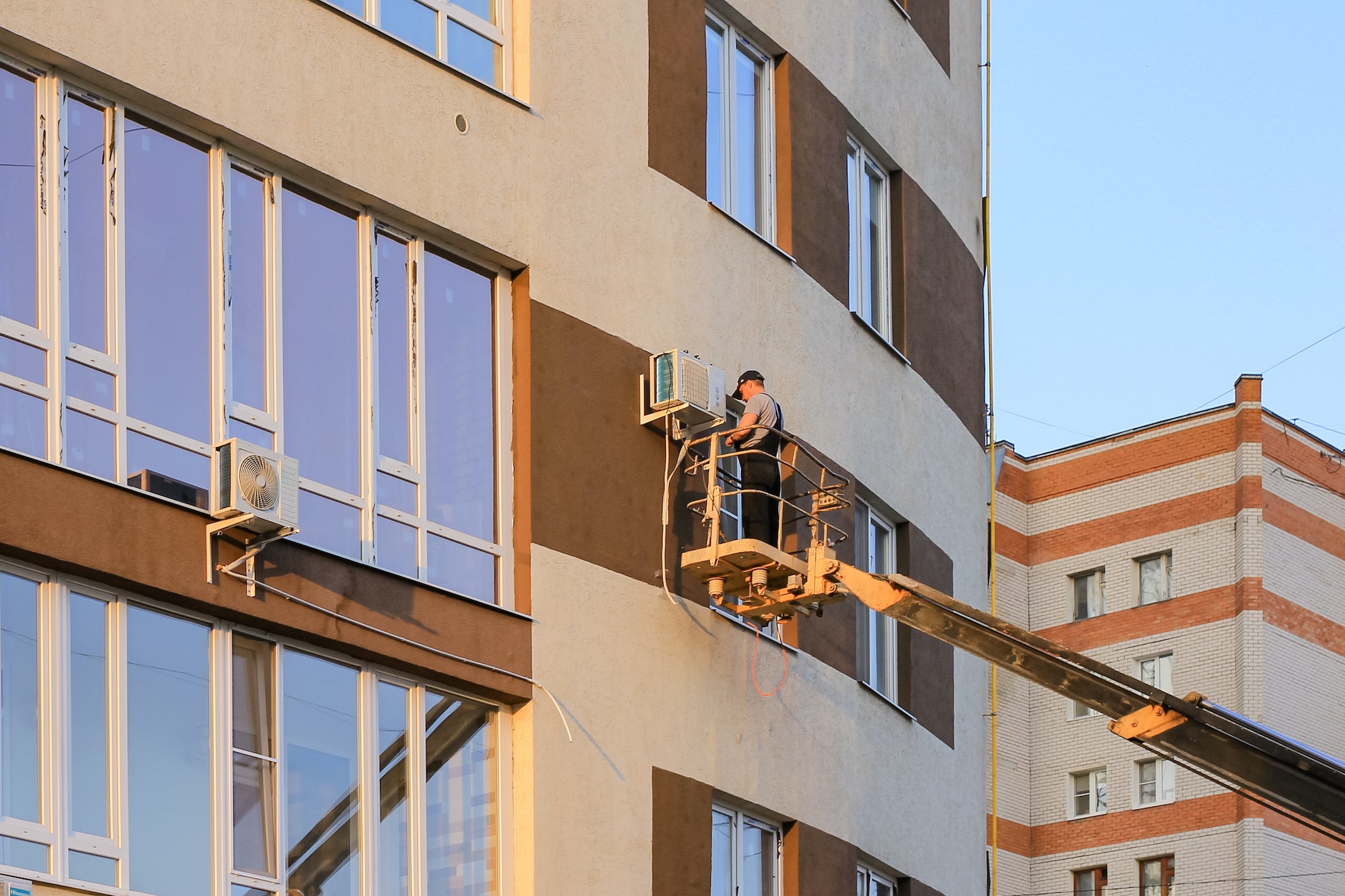 Industrial technician, engineer installing air conditioner on the facade of the house. N